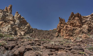 Kaya oluşumları ve lav akıntıları Roques de Garcia 'da görünür uyduyla mavi gökyüzünün altında akar.