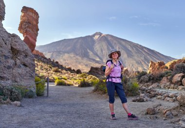 Sırt çantalı kadın yürüyüşçü, güneşli bir günde arka planda Teide Dağı ile Roques de Garcia yakınlarında duruyor.