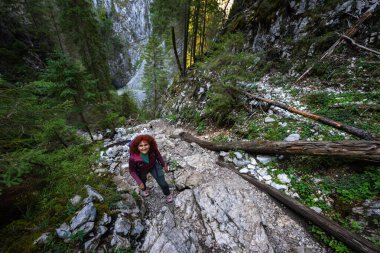 Hiker woman with backpack going uphill on a rocky mountain trail in Apuseni, Romania