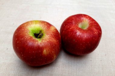 Beyaz taneli kumaş paspasa yerleştirilmiş iki kırmızı elma görüntüsü