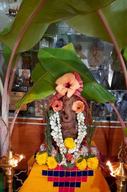 Kızıl toprakta puja gösterisi, çiçek ve çelenkle süslenmiş Ganesha Idol