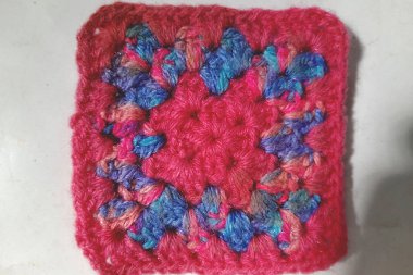 Pembe ve mavinin daha yakın görüntüsü, yünlü, örülmüş masa minderi dekoratif ve koruyucu amaçlar için kullanılır.