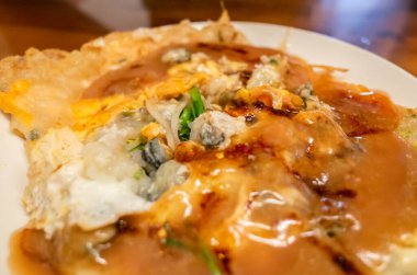 Kadınlar geleneksel Tayvan usulü istiridye omleti yerler.