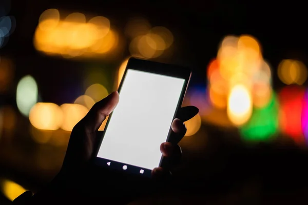woman hold a cellphone with blank white screen at night