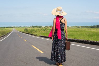 Asyalı bir kadın elinde bir mahsul tutup açık havada yürüyor. Seyahat kavramı.