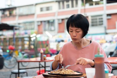 Yetişkin bir kadın Tayvan 'da gece yarısı bifteğini sokakta yer.