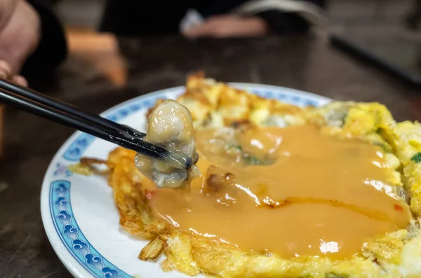 woman eat traditional Taiwanese snack of oyster omelet