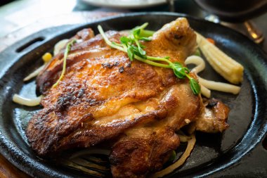 Cızırdayan bir tabakta servis edilen kızarmış tavuk bifteği.