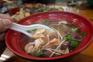 Domuz organlı çorba, yeşil soğan, kırmızı kasede servis edilir.