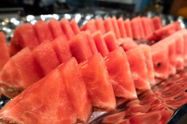 Yansıtıcı tabakta düzgün dizilmiş karpuz dilimleri.