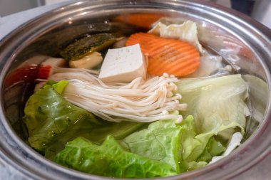 Metal bir tencerede sebzeli, tofu ve mantarlı güveç..