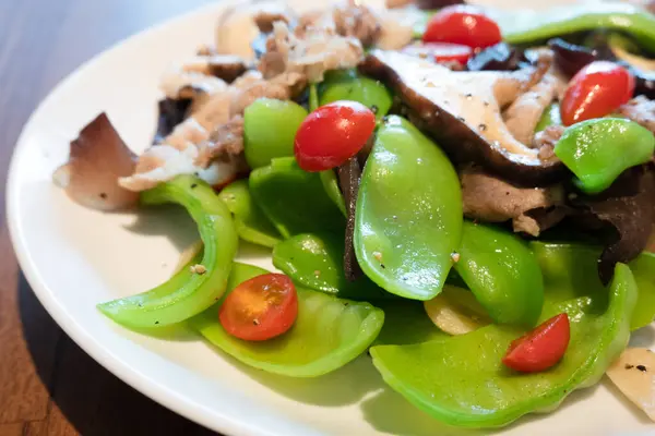 stock image A vibrant stir-fried dish featuring fresh snow peas, tender beef, mushrooms, and cherry tomatoes.