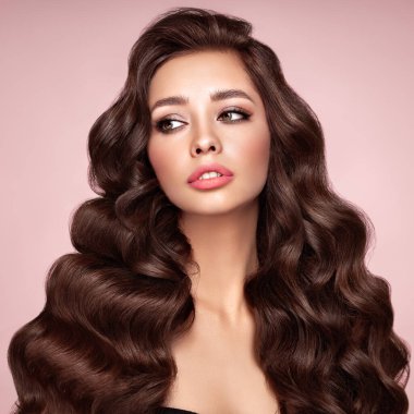 Mükemmel makyajlı esmer kız. Uzun kıvırcık saçlı, gülümseyen güzel model kadın. Bakım ve güzellik saç ürünleri.