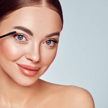 Makyaj fırçasıyla kirpiklerine siyah rimel süren güzel bir kadın. Kirpik uzantıları. Makyaj, kozmetik. Güzellik, cilt bakımı