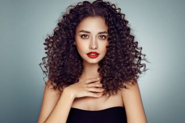 Saçları kıvırcık, gülümseyen güzel bir kadının moda stüdyo portresi. Moda ve güzellik