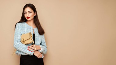 Mavi ceketli esmer kadın. Takım elbise giymiş bir model. Bej çantalı kız. Moda fotoğrafı.