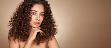 Saçları kıvırcık, gülümseyen güzel bir kadının moda stüdyo portresi. Moda ve güzellik