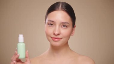 Genç bir kadının portresi, yüzünün kremlerini kullanıyor. Taze nemlendirilmiş cilt, güzel yakın plan kozmetik yüz, mutlu sağlıklı model. Yüz kremi şişesi olan bir model. Yavaş çekim