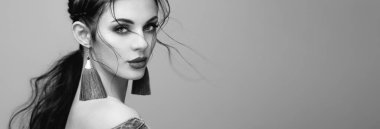 Mükemmel makyajlı esmer kız. Kıvırcık saçlı güzel bir model kadın. Bakım ve güzellik ürünleri. Saçları örgülü bir kadın. Mücevherleri olan bir model. Siyah beyaz fotoğraf