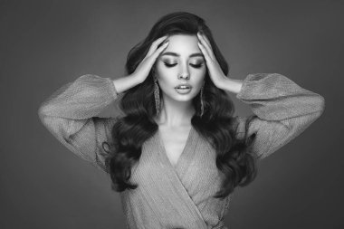 Mükemmel makyajlı esmer kız. Uzun kıvırcık saçlı, gülümseyen güzel model kadın. Bakım ve güzellik ürünleri. Modaya uygun siyah beyaz fotoğraf.