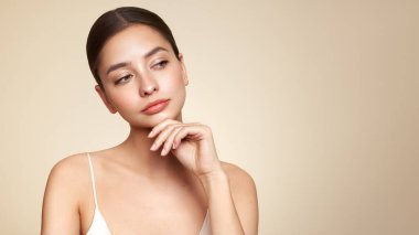 Temiz tenli güzel bir genç kadın portresi. Sağlıklı ciltli bir model. Kozmetik, güzellik ve kaplıca. Boş boşluğa bakan model
