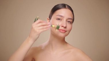 Doğal bir yeşim taşlı rulo kullanırken rahat ve gülümseyen genç bir kadının videosunu kapat. Deri silindirli yaşlanma önleyici ve kozmetik temizlik için yüz bakımı. Yavaş çekim