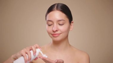Young woman washes face with face wash foam. Daily facial skin care routine. Closeup view, slow motion 4K footage