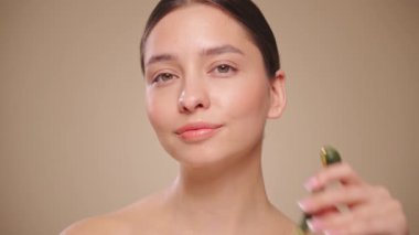 Doğal bir yeşim taşlı rulo kullanırken rahat ve gülümseyen genç bir kadının videosunu kapat. Deri silindirli yaşlanma önleyici ve kozmetik temizlik için yüz bakımı. Yavaş çekim