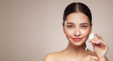 Genç ve güzel bir kadın pipetle yüz serumu uyguluyor. Yüz bakımı için estetik prosedürler