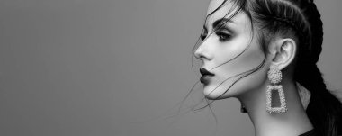 Mükemmel makyajlı esmer kız. Kıvırcık saçlı güzel bir model kadın. Bakım ve güzellik ürünleri. Saçları örgülü bir kadın. Mücevherleri olan bir model. Siyah beyaz fotoğraf