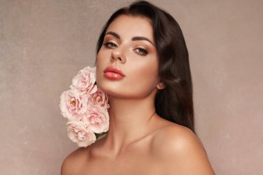 Temiz tenli güzel bir genç kadın portresi. Sağlıklı ciltli bir model, yakın portre. Kozmetik, güzellik ve kaplıca. Gül çiçekli kız.