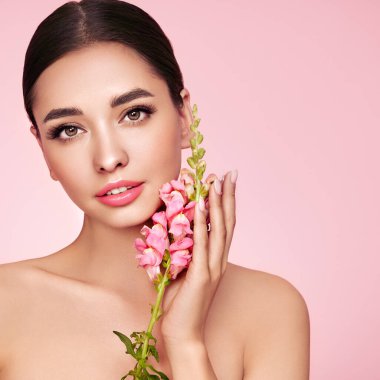 Temiz tenli güzel bir genç kadın portresi. Sağlıklı ciltli bir model, yakın portre. Kozmetik, güzellik ve kaplıca. Pembe çiçekli kız