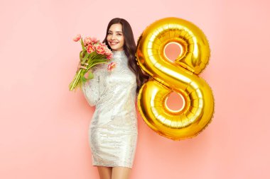 Güzel genç bir kadın elinde bir buket lale çiçeği ve 8 numaralı balon ile bahar tatilini kutluyor. 8 Mart Kadınlar Günü