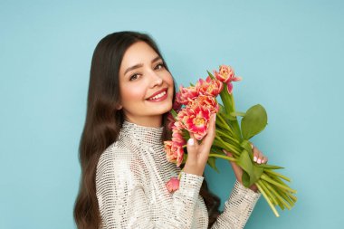 Mavi arka planda pembe lale buketi olan mutlu bir kadın. 8 Mart kutlamaları