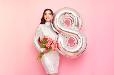 Güzel genç bir kadın elinde bir buket lale çiçeği ve 8 numaralı balon ile bahar tatilini kutluyor. 8 Mart Kadınlar Günü