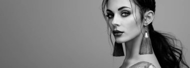 Mükemmel makyajlı esmer kız. Kıvırcık saçlı güzel bir model kadın. Bakım ve güzellik ürünleri. Saçları örgülü bir kadın. Mücevherleri olan bir model. Siyah beyaz fotoğraf