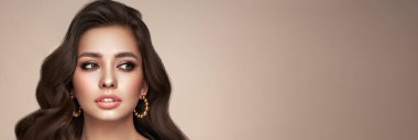 Mükemmel makyajlı esmer kız. Uzun kıvırcık saçlı, gülümseyen güzel model kadın. Bakım ve güzellik saç ürünleri.