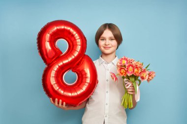 Lale buketi ve 8 numaralı balonla neşeli mutlu çocuk. Mavi arka planda gülümseyen çocuk, bahar tatilini kutluyor. 8 Mart Kadınlar Günü