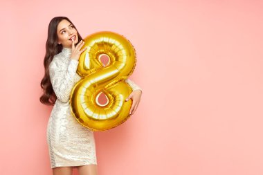 8 numaralı balonu tutan şenlikli elbisesiyle genç ve güzel bir kadın bahar tatilini kutluyor. 8 Mart Kadınlar Günü