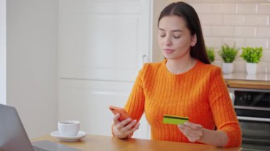 Genç, çekici bir kadın, kredi kartıyla dizüstü bilgisayarla online alışveriş yapıyor. E-ticaret, iş konsepti. Serbest, uzak çalışma