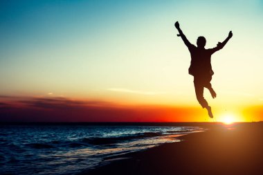 Siluet genç kadın ile el kadar sahilde günbatımı atlama. Seyahat fotoğraf yaz