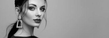 Mükemmel makyajlı esmer kız. Kıvırcık saçlı güzel bir model kadın. Bakım ve güzellik ürünleri. Saçları örgülü bir kadın. Mücevherleri olan bir model. Siyah beyaz fotoğraf