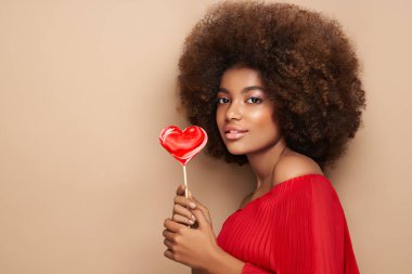 Kalp şeklinde lolipopu olan Afrikalı bir kızın güzel portresi. Sevgililer Günü. Aşkın sembolü