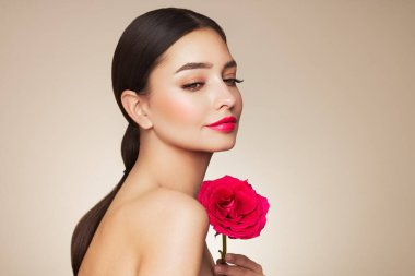 Parlak esmer saçlı güzel bir genç kadın. Gül çiçekli kız. Sağlıklı ciltli bir model. Kozmetik, güzellik ve kaplıca