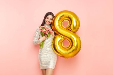 Güzel genç bir kadın elinde bir buket lale çiçeği ve 8 numaralı balon ile bahar tatilini kutluyor. 8 Mart Kadınlar Günü