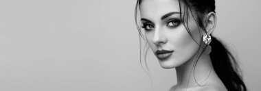 Mükemmel makyajlı esmer kız. Kıvırcık saçlı güzel bir model kadın. Bakım ve güzellik ürünleri. Saçları örgülü bir kadın. Mücevherleri olan bir model. Siyah beyaz fotoğraf