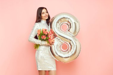 Güzel genç bir kadın elinde bir buket lale çiçeği ve 8 numaralı balon ile bahar tatilini kutluyor. 8 Mart Kadınlar Günü