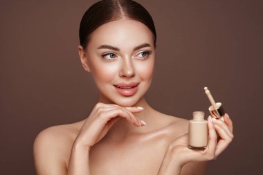 Temiz tenli güzel bir genç kadın portresi. Makyaj şişesi olan bir model. Kozmetik, güzellik ve kaplıca