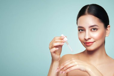 Genç ve güzel bir kadın pipetle yüz serumu uyguluyor. Yüz bakımı için estetik prosedürler