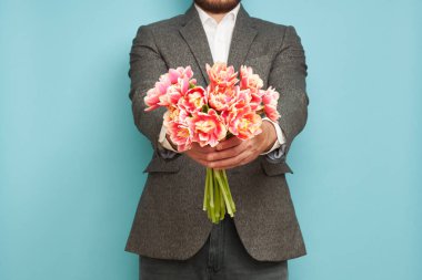 Takım elbiseli romantik bir adam, mavi arka planda bir buket lale, Sevgililer Günü, 8 Mart